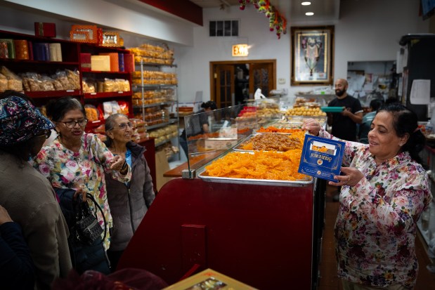 Dina Sukhadia helps customers at the sweets counter at Sukhadia's Sweets and Snacks on Devon Avenue on Oct. 30. 2024. (E. Jason Wambsgans/Chicago Tribune)