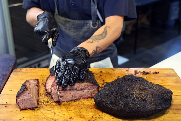 Nestor Aguayo, a cook at Sanders BBQ Supply Co. on West 99th Street in Chicago, slices brisket on Nov. 21, 2024. (Terrence Antonio James/Chicago Tribune)