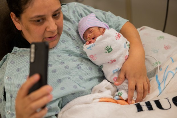 Eufemia Almanza holds her grandson, Hugo Beltran, while FaceTiming his mother in Mount Sinai Hospital's Neonatal Intensive Care Unit in Chicago on Oct. 4, 2024. (Tess Crowley/Chicago Tribune)