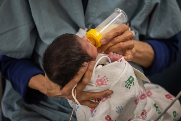 Nurse R.G. Alanes feeds a premature baby their mother's breast milk in Mount Sinai Hospital's Neonatal Intensive Care Unit in Chicago on Oct. 4, 2024. The infant was born at 3 pounds, 14.4 ounces at birth on Sept. 16. (Tess Crowley/Chicago Tribune)