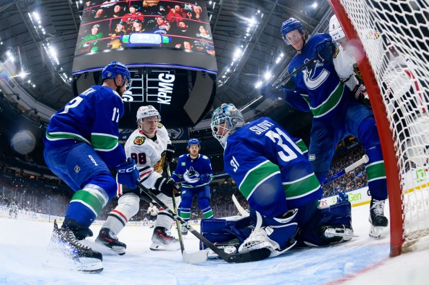 The Canucks' Filip Hronek (17) and Arturs Silovs (31) defend the Blackhawks' Connor Bedard durng the third period Saturday. (Derek Cain/Getty Images)