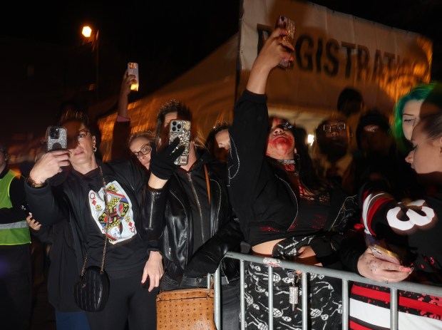 Parade watchers take pictures during the Haunted Halsted Halloween Parade in Lakeview on Oct. 31, 2024. (John J. Kim/Chicago Tribune)