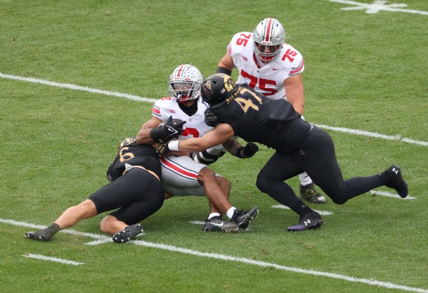 Ohio State wide receiver Emeka Egbuka (2) is tackled by Northwestern defensive back Robert Fitzgerald (6) and defensive lineman Michael Kilbane (47) in the first quarter at Wrigley Field on Nov. 16, 2024, in Chicago. (John J. Kim/Chicago Tribune)