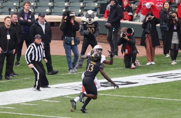 Ohio State wide receiver Jeremiah Smith (4) eyes the ball as Northwestern defensive back Josh Fussell (13) defends in the first quarter at Wrigley Field on Nov. 16, 2024, in Chicago. A touchdown call on the play was overturned after video review. (John J. Kim/Chicago Tribune)