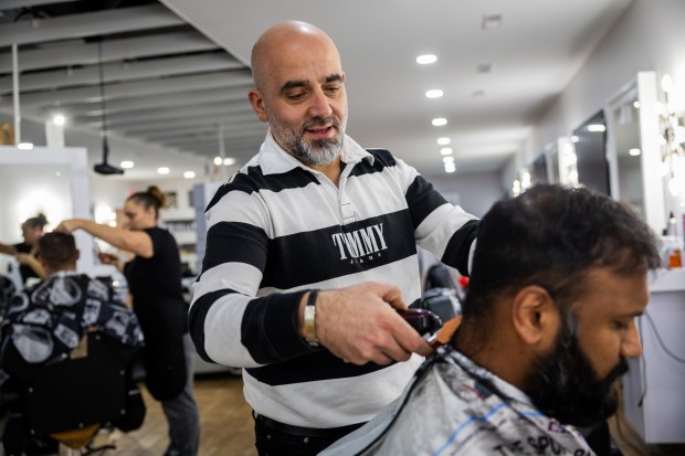 Bob Khoury, owner of two barber shops, cuts Vijay Kuchhangi's hair in Peoria on Nov. 20, 2024. Khoury moved to Peoria from Aitou and his uncle immigrated 35 years ago. (Tess Crowley/Chicago Tribune)