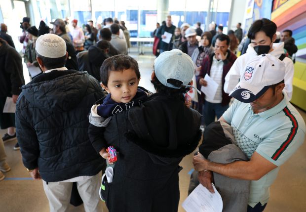 Mehid Aayan, 2, is held by his father, Maung Nu, as Nu waits to vote at an early voting center at the Chicago Public Library's Northtown branch in the West Ridge neighborhood on Nov. 1, 2024. Nu and his son are immigrants from the Rohingya muslim community of northwestern Myanmar. (Chris Sweda/Chicago Tribune)