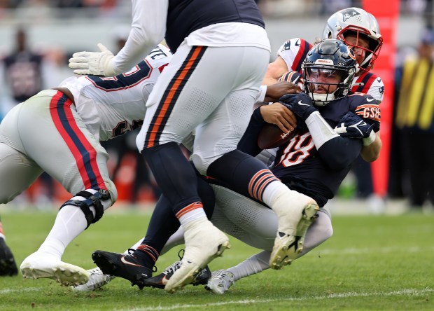 Bears quarterback Caleb Williams is sacked by Patriots defensive end Keion White, left, and safety Brenden Schooler in the third quarter on Nov. 10, 2024, at Soldier Field. (Chris Sweda/Chicago Tribune)