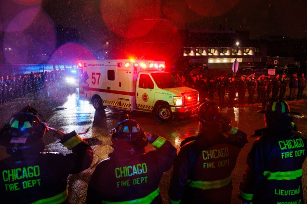 Members of the Chicago fire and police departments salute in the rain outside the Cook County medical examiner's office on Nov. 5, 2024, as an ambulance arrives carrying the body of Officer Enrique Martínez, 26, who was fatally shot Monday night in the 8000 block of South Ingleside Avenue in the Chatham neighborhood. (Armando L. Sanchez/Chicago Tribune)