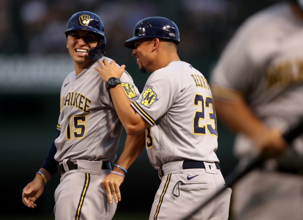 Milwaukee Brewers player Tyrone Taylor (15) and first base coach Quintin Berry (23) have a laugh at first base after Taylor drove in a run with a single in the first inning of a game against the Chicago Cubs at Wrigley Field in Chicago on Wednesday, Aug. 11, 2021. (Chris Sweda/Chicago Tribune)