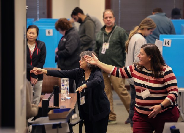 Election judges Lisa Rottenberg, left, and Nancy Naughton direct people to empty voting booths in the Arlington Heights Village Hall on Oct. 28, 2024. (Stacey Wescott/Chicago Tribune)