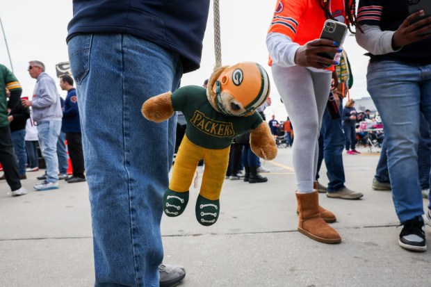 Michael Miller, 68, holds a bear dressed as a Green Bay Packers' player on a rope while tailgating. (Armando L. Sanchez/Chicago Tribune)