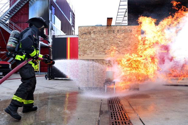 Chicago firefighter Markeith Jenkins douses a burning turkey fryer during a safety demonstration at the Quinn Fire Academy, Nov. 20, 2024. A frozen turkey was lowered into a too-full pot of hot oil, which caused the fire. (Antonio Perez/Chicago Tribune)