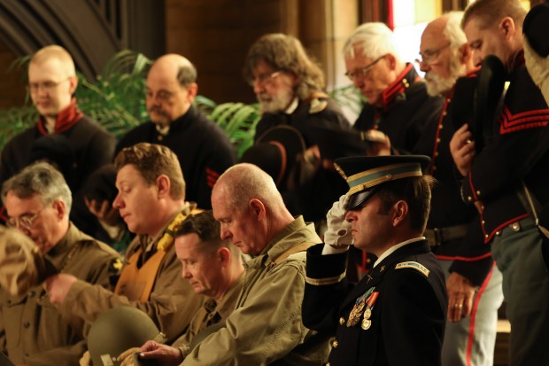 Capt. Anthony Catella of the 1st Illinois Civil Support Battalion, bottom right, puts on his hat after a benediction for a Veterans Day observance and ceremony in May Chapel on Nov. 9, 2024. (John J. Kim/Chicago Tribune)