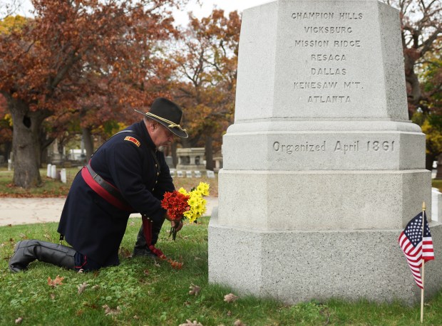 Ed McGlade of the Chicago Light Artillery Battery B reenactment group places flowers at a gravesite for soldiers of the original Civil War unit following a Veterans Day observance and ceremony at Rosehill Cemetery. (John J. Kim/Chicago Tribune)