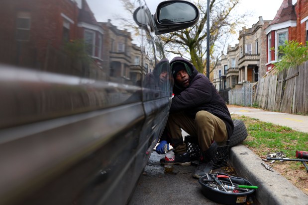 Dee Mitchell changes his brakes outside of his home along the 1600 block of South Homan Avenue on Nov. 19, 2024, in Chicago. Mitchell is a long-time resident of North Lawndale and lives on a block with lots of empty lots. (Stacey Wescott/ Chicago Tribune)