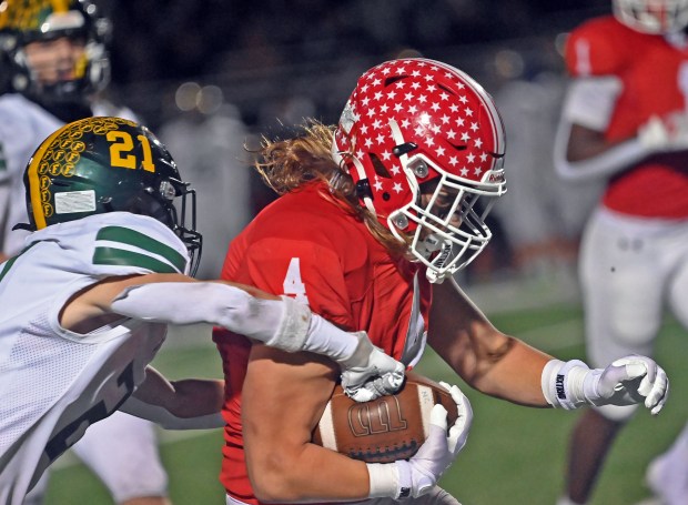 Naperville Central's Aaron Nussbaum hangs onto the ball despite Fremd's Joe Gump trying to punch the ball out. Naperville Central defeated Fremd 31-28 in the second round of the Class 8A football playoffs, Friday, Nov. 8, 2024, in Naperville, Illinois. (Jon Langham/for the Naperville Sun)