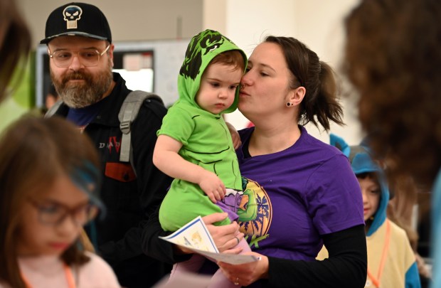 Natalia Karolkiewicz of Deerfield gives a kiss to daughter Nova, 19 months. On left is Nova's father Sebastian Karolkiewicz at the Mini Comic Con at the Vernon Area Public Library on Nov. 16, 2024 in Lincolnshire (Karie Angell Luc/Pioneer Press)