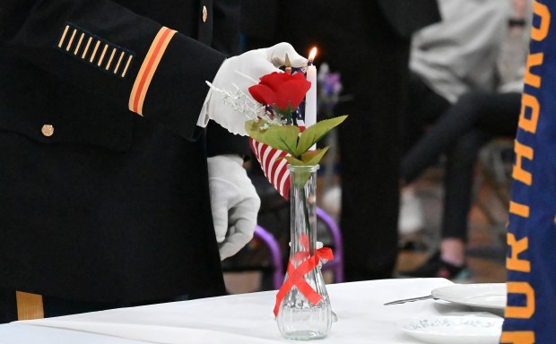 Northbrook American Legion George W. Benjamin Post 791 Commander James Ossey of Glenview lights the candle at the Fallen Comrade Table memorial during the Veterans Day Ceremony at Northbrook Junior High in Northbrook on Nov. 11, 2024. (Karie Angell Luc/Pioneer Press)