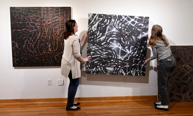 Indiana University Northwest Director of Arts Programming Erin McHugh, left, and gallery assistant Abigail Svitko prepare to place one five paintings in Portage High School art teacher Jeremy Boyer's work titled Pantomime while setting up for the 2024 Biennial Regional Educators Exhibition at the Savanah Gallery at IUN in Gary, Indiana Friday Nov. 15, 2024. The exhibit is scheduled to open Monday, Nov. 18. (Andy Lavalley/for the Post-Tribune)