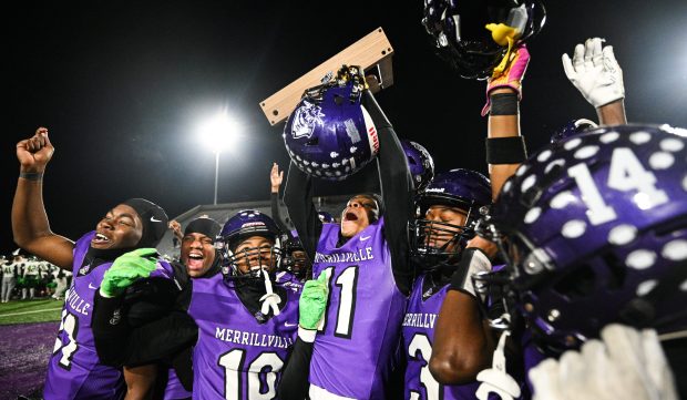 Merrillville wide receiver John Peters, surrounded by teamates, hoists his team's trophy after their win against Valparaiso in the Class 5A Regional championship game on Friday, Nov. 15, 2024. (Kyle Telechan/for the Post-Tribune)