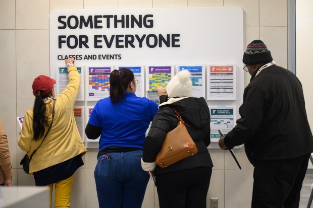 Visitors look over a schedule of classes and events during a tour of the newly-opened Hammond YMCA on Friday, Nov. 22, 2024. (Kyle Telechan/for the Post-Tribune)