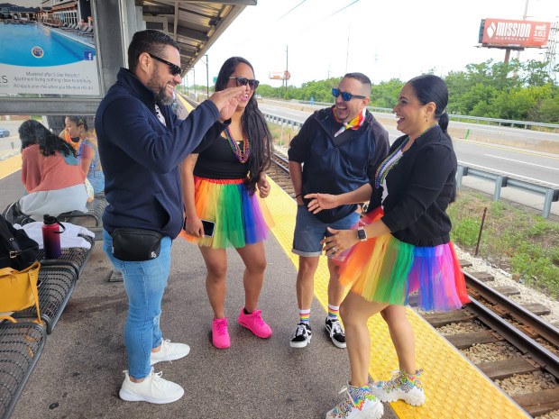 Enrique Abello, left, makes friends Mago Candanoza, center left; Luciano Labrabor, center right; and Angie Gibbons, right, laugh as they wait for the South Shore train to pick them up for the Chicago Pride Parade June 30. (Michelle L. Quinn/Post-Tribune)