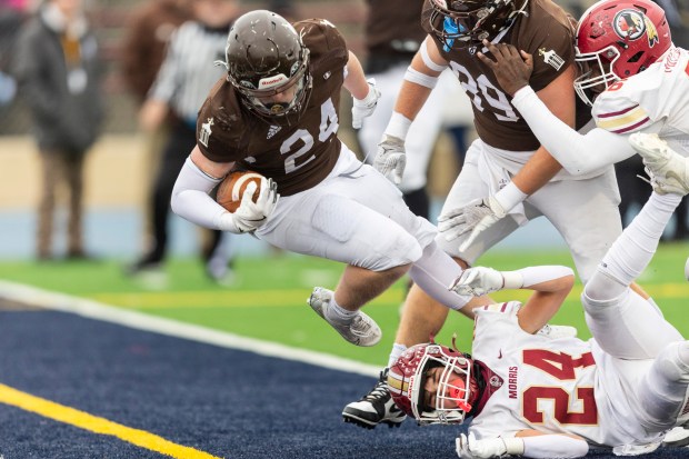 Joliet Catholic's Larry Stringham (24) falls over Morris' Steven Wagner (24) and into the end zone for a touchdown in the Class 5A state semifinals at Memorial Stadium in Joliet on Saturday, Nov. 23, 2024. (Vincent D. Johnson / for the Daily Southtown)