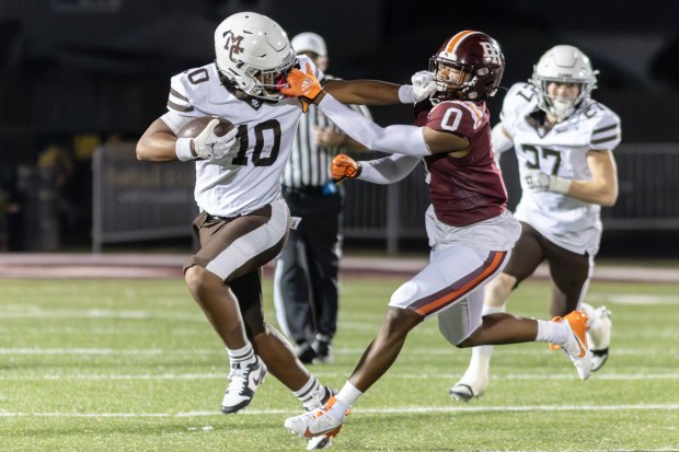 Mount Carmel's Danyil Taylor Jr. (10) and Brother Rice's Donovan Brown (0) grab each other by the face mask during a CCL/ESCC Blue conference game in Chicago on Friday, Oct. 4, 2024. (Troy Stolt / Daily Southtown)