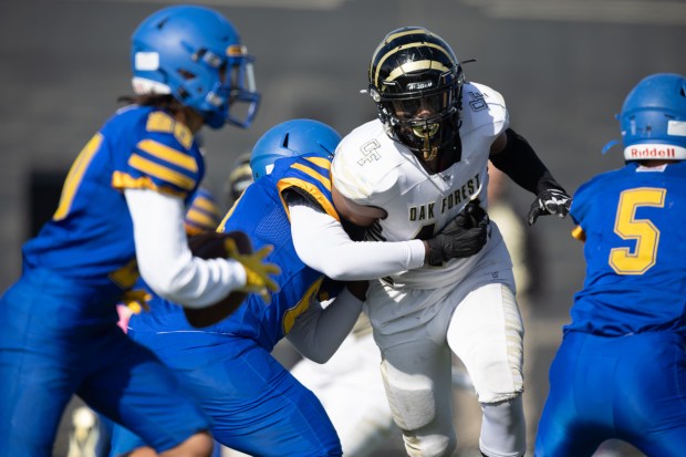 Oak Forest's Kevin Epinger, center, gets past a Kennedy lineman on his way to the quarterback in the Class 6A first-round game at Lane Stadium in Chicago on Saturday, Nov. 2, 2024. (Vincent D. Johnson / for the Daily Southtown)