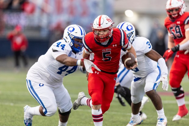 St. Rita's Steven Armbruster (5) brushes off a tackle by Quincy's Maxwell Wires (44) as he scrambles out of the pocket in the Class 7A state quarterfinals in Chicago on Saturday, Nov. 16, 2024. (Vincent D. Johnson / for the Daily Southtown)