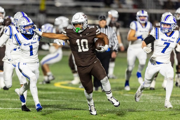 St. Charles North's Jack Shannon (1) get's a stiff arm from Mount Carmel's Danyil Taylor (10) as he hits his stride on a big run during the Class 7A second-round game in Chicago on Saturday, Nov. 9, 2024. (Vincent D. Johnson / for the Daily Southtown)