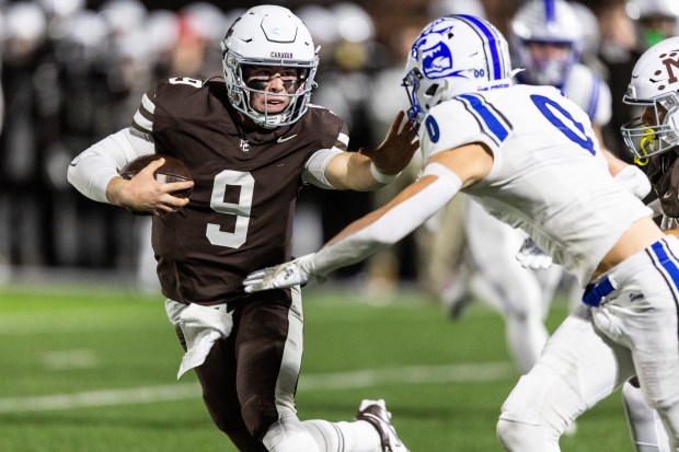 Mount Carmel quarterback Jack Elliott (9) tries to hold off St. Charles North's Aidan McClure (0) as he runs out of the backfield during the Class 7A second-round game in Chicago on Saturday, Nov. 9, 2024. (Vincent D. Johnson / for the Daily Southtown)