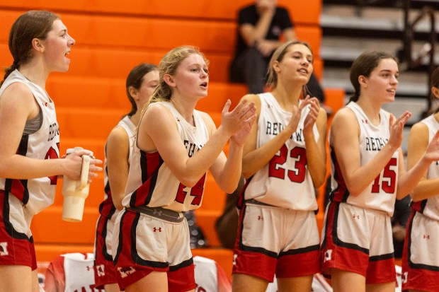 Marist's Chloe Mlyniec (24), Olivia Barsch (23) and Rose Cosme (15) cheer after a basket against Shepard during the Bobby Bolton Classic in Palos Heights on Tuesday, Nov. 19, 2024. (Vincent D. Johnson / for the Daily Southtown)