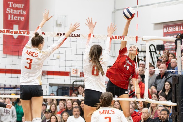 Marist's Maggie Kurpeikis (14) spikes the ball against Mother McAuley during the Class 4A Marist Sectional final match in Chicago on Thursday, Nov. 7, 2024.