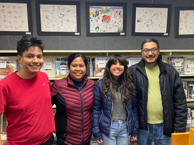 Juliana Bosch, an Evergreen Park Community High School junior, stands with family members in front of her 1980s-themed artwork, during Evergreen Park Public Library's Nov. 12 Inktober Exhibit artist reception. (Evergreen Park Public Library)