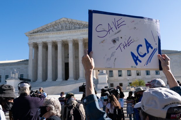 A demonstrator holds a sign outside the U.S. Supreme Court as arguments are heard about the Affordable Care Act, Nov. 10, 2020, in Washington. (Alex Brandon/AP)