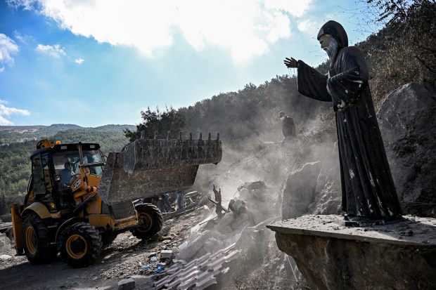 A statue of the 19th-century Maronite Christian St. Mar Charbel stands as a bulldozer clears debris from the site of a Israeli air strike on the village of Aitou in northern Lebanon on Oct. 15, 2024. (Joseph Eid/Getty-AFP)