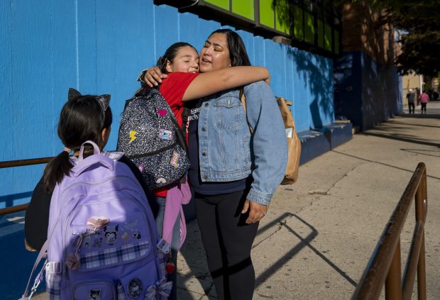 Rocio Lugo, right, says goodbye to Brianna Isaula, center, and her daughter Penelope Mena after walking them and other students from Telpochcalli Elementary School to an after school program at the Boys and Girls Club in Little Village on Oct. 21, 2024. (Brian Cassella/Chicago Tribune)