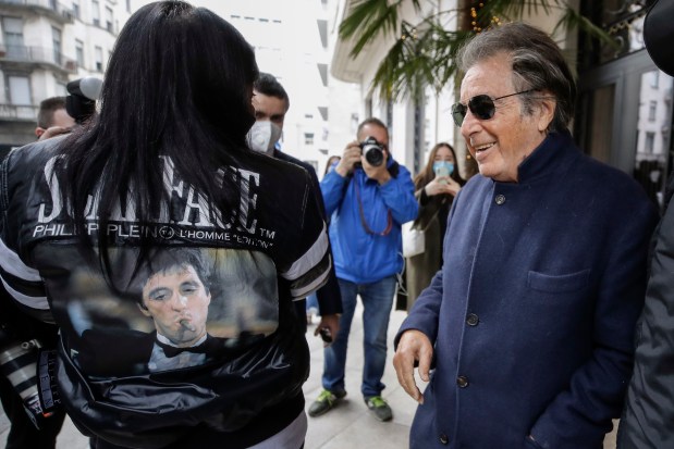 Al Pacino, a cast member of the movie "House of Gucci," leaves a hotel in Milan, Italy, on March 11, 2021, while Stefania Nobile shows Pacino her leather jacket with a photo from the movie "Scarface." (Luca Bruno/AP)