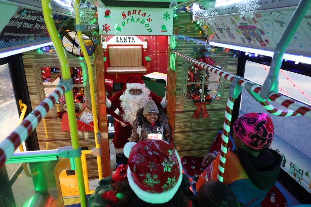 Santa Claus sits with Tyreianna Mabrey on a CTA holiday bus at the corner of Jackson Boulevard and Austin Avenue on Dec. 8, 2023, in Chicago. (John J. Kim/Chicago Tribune)