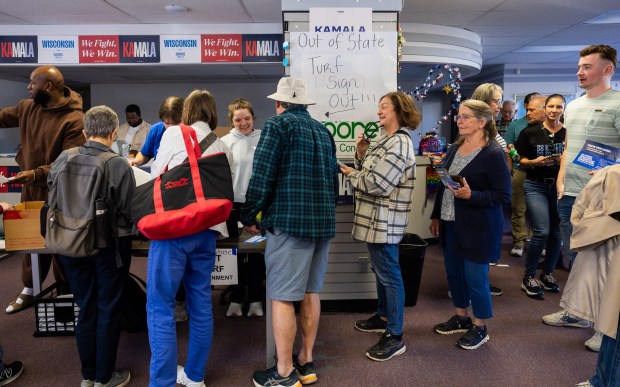 Volunteers who drove from Evanston to Milwaukee, Wisconsin wait in line to check in at the Democratic Party of Milwaukee County office before knocking on doors in Milwaukee as part of Operation Swing State on Oct. 19, 2024. (Tess Crowley/Chicago Tribune)