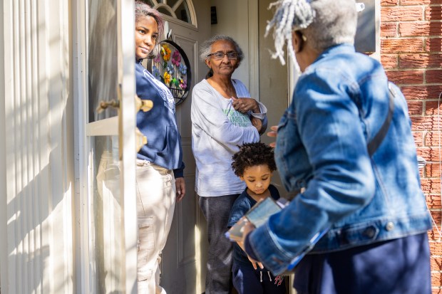 Loretta Jackson, right, a volunteer from the Democratic Party of Evanston, talks to Margaret Cannon, center, granddaughter Mikyah Gandy, and great-grandson Adonis Robinson, 3, on Oct. 19, 2024, at Cannon's door in Milwaukee as part of Operation Swing State. (Tess Crowley/Chicago Tribune)