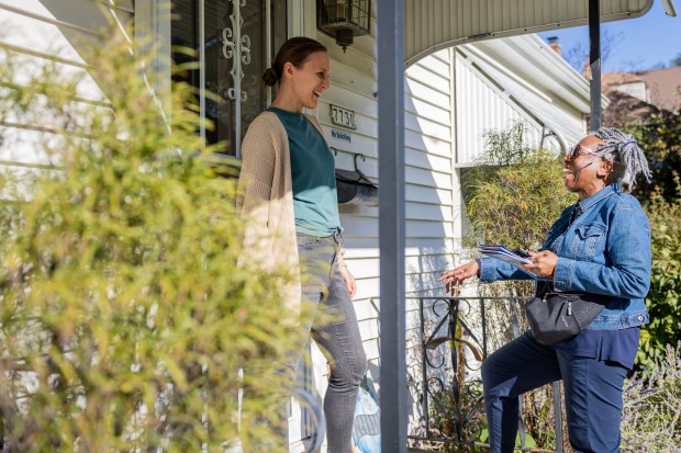 Loretta Jackson, volunteer from the Democratic Party of Evanston, right, talks to Ashley Groth about candidates after knocking on Groth's door in Milwaukee, Wisconsin on Oct. 19, 2024. (Tess Crowley/Chicago Tribune)