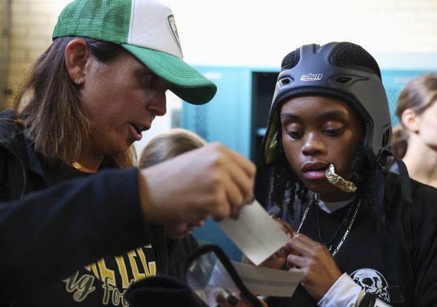 Coach Caroline Schwartz shows new plays to Jocelyn Hale in the locker room before their first sectional game against Morton High School at Winnemac Stadium on Oct. 15, 2024. (Eileen T. Meslar/Chicago Tribune)