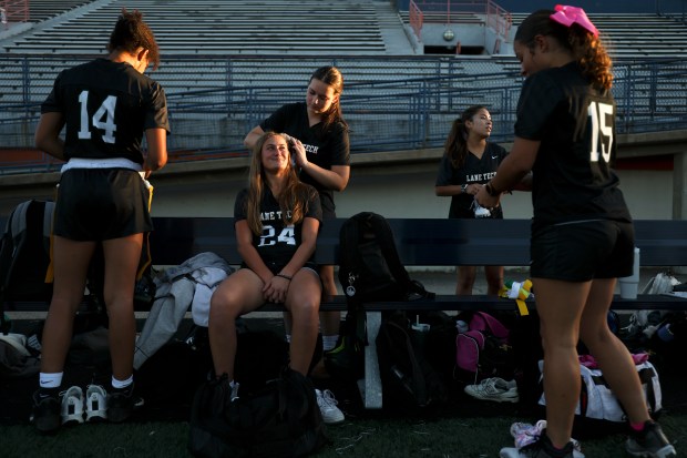 Lane Tech's Maggie Yoest braids Gianna Phillips hair as their teammates get ready before the first game of their Oak Park-River Forest Regional in Oak Park on Tuesday, Oct. 8, 2024. (Eileen T. Meslar/Chicago Tribune)