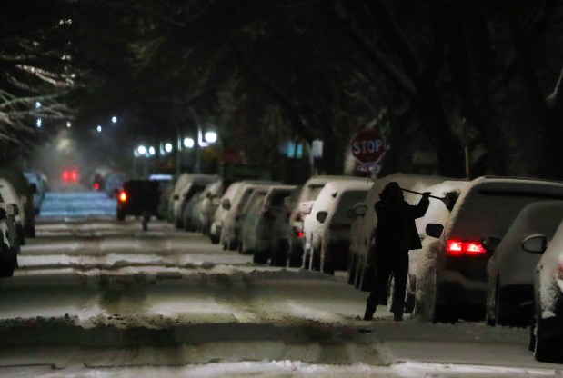 Snow is swept off a car in Chicago's Irving Park neighborhood, Jan. 26, 2021. (José M. Osorio/ Chicago Tribune)