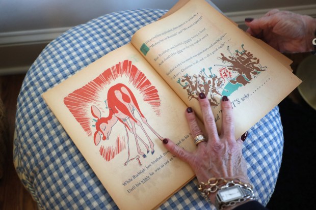 Martha May pages through her father, Robert May's, original book of Rudolph the Red-Nosed Reindeer at her home on Dec. 17, 2021 in Lake Forest. The paper book was handed out by Montgomery Ward in 1939.