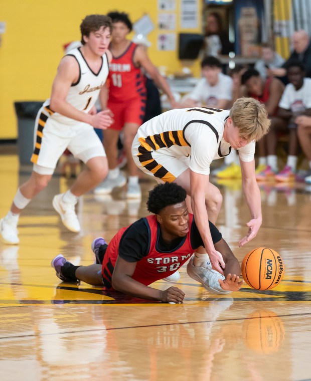 South Elgin's Darrion Thurman, bottom, battles for a loose ball with Jacobs' Carson Goehring during their game in the 2024 Hinkle Holiday Classic basketball tournament at Jacobs High School in Algonquin on Saturday, Dec. 21, 2024. (Ryan Rayburn/for the Aurora Beacon News)