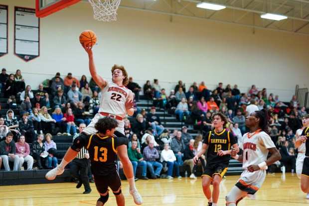 Sandwich's Dom Rome (22) drives to the basket over Harvard's Christian Pagles (13) during a basketball game at Sandwich High School on Wednesday, Dec. 18, 2024. (Sean King / for The Beacon-News)