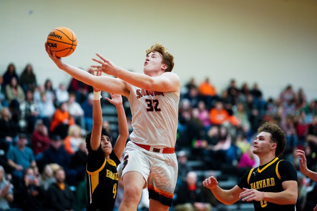 Sandwich's Quinn Rome (32) drives to the basket against Harvard's Julian Acosta (4) and Adam Cooke (0) during a basketball game at Sandwich High School on Wednesday, Dec. 18, 2024. (Sean King / for The Beacon-News)